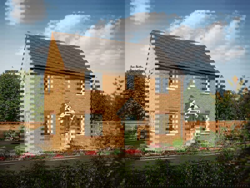 A large, two-storey home with lots of windows and a light green door way surrounded by blooming flower-beds
