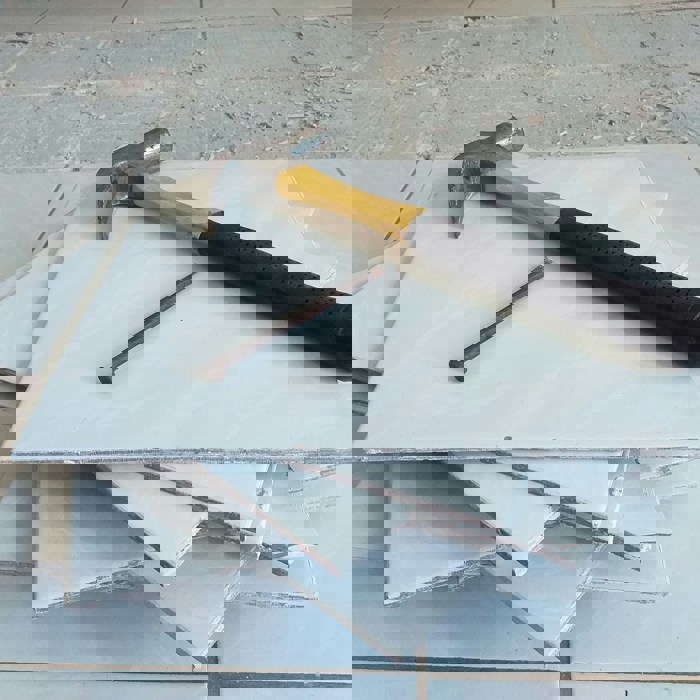 A hammer and nail on a stack of tiles